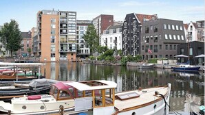 Een gracht met aangemeerde boten, omringd door historische gebouwen met uiteenlopende architectuur.