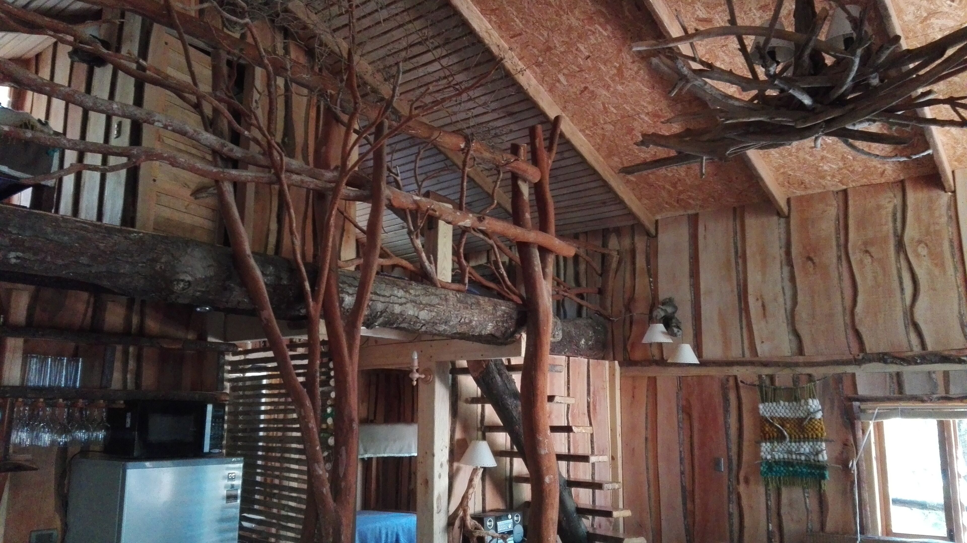 Ein rustikaler Innenraum mit freiliegenden Holzbalken, einer Holzzahlendele und rustikaler Einrichtung, darunter eine Lampe und eine Wanddekoration.