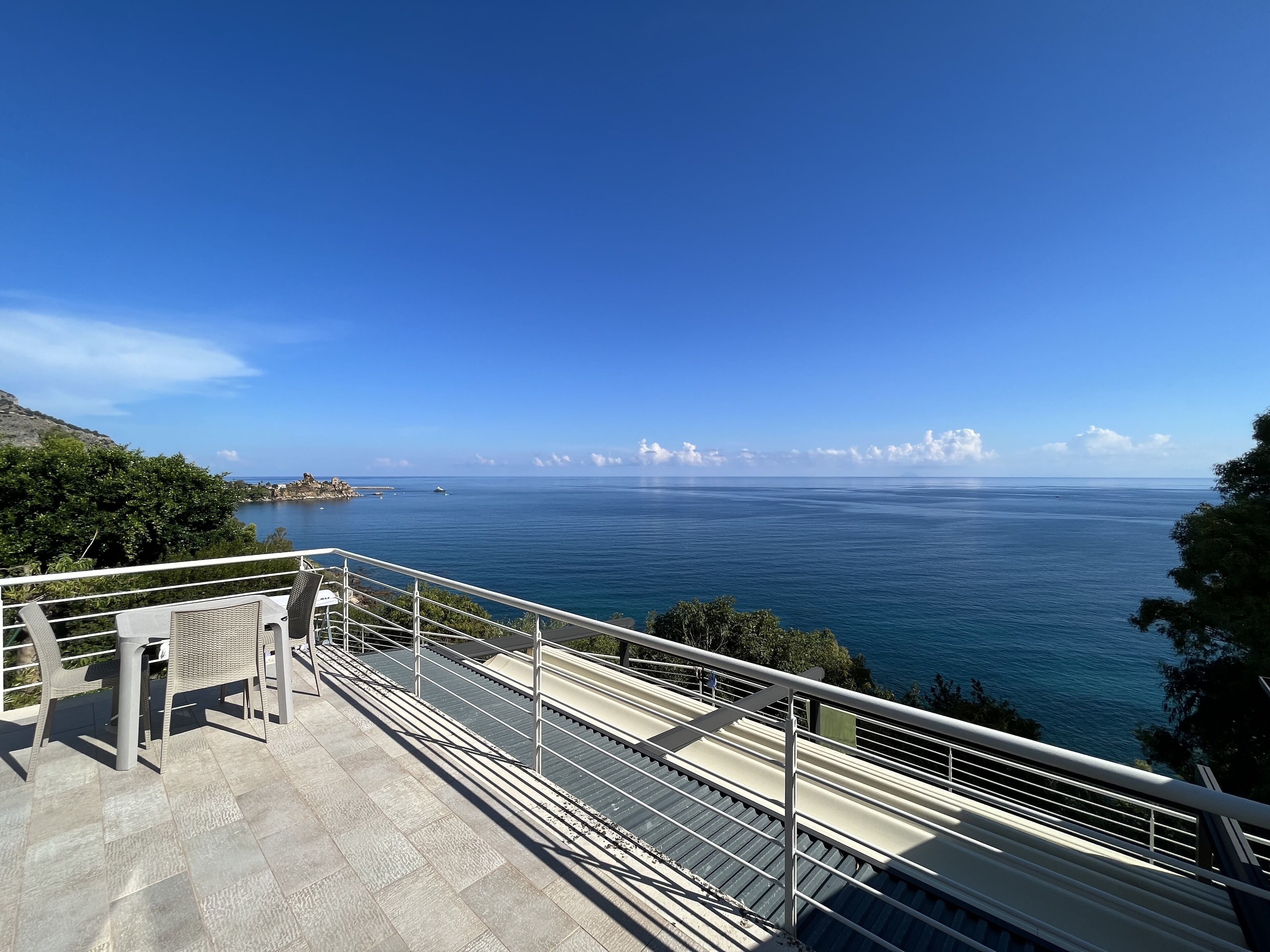 A balcony with a view of the sea and distant coastline.