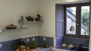 A compact kitchen with white cabinets, a blue countertop, and a window with a view of a brick building. - In Anjou in the castle vegetable garden, Peace, flower and vegetable (Marans)