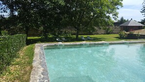 A clear swimming pool with stone edging, surrounded by a grassy area and trees. - In Anjou in the castle vegetable garden, Peace, flower and vegetable (Marans)