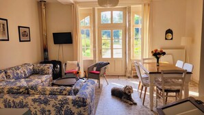 A cozy living room with a sofa, a chair, a small table with a vase of flowers, and a dog lying on the floor. - In Anjou in the castle vegetable garden, Peace, flower and vegetable (Marans)