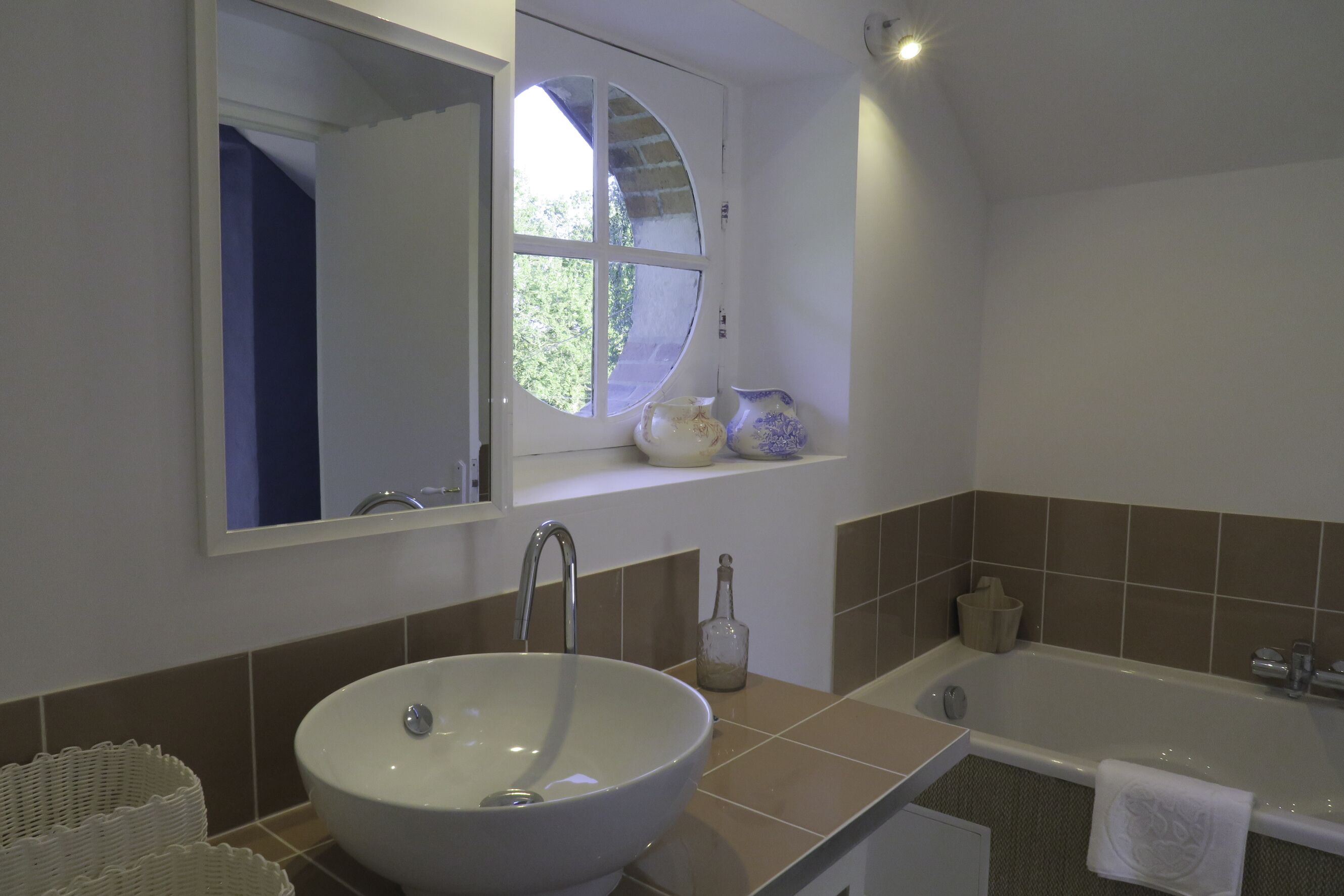 Une salle de bain avec un grand lavabo, une baignoire, une fenêtre avec vue et un miroir au-dessus du lavabo.