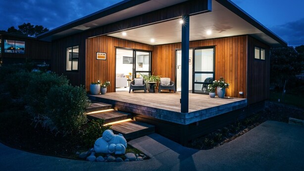A modern house with a wooden exterior, a covered porch, and a landscaped garden. - Guest House on Queens (Waiheke Island)