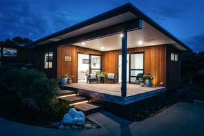 Une maison moderne avec une façade en bois, un porche abrité et un jardin aménagé.