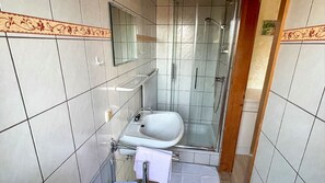 Ein kleines Badezimmer mit Dusche, Waschbecken und Spiegel.