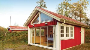 A small, red wooden house with a large glass door and windows, surrounded by trees and grass. - Amazing home in Hästveda with WiFi (Hästveda)