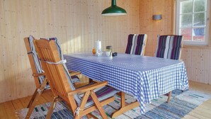A wooden-paneled room with a table set for two, featuring a checkered tablecloth, striped cushions, and a green pendant light. - Amazing home in Hästveda with WiFi (Hästveda)