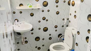 A bathroom with a toilet, sink, and mirror. The walls have a circular pattern.
