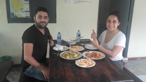 Dos personas sentadas en una mesa de madera con varios platos frente a ellas.