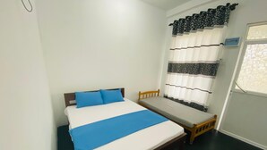 Una cama individual con una colcha azul, cabecera de madera y una mesita de noche pequeña.