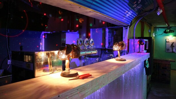 A bar area with a long counter, various bar equipment, and a ceiling with exposed pipes and lighting. - gangneung sol guesthouse - Hostel (Gangneung)