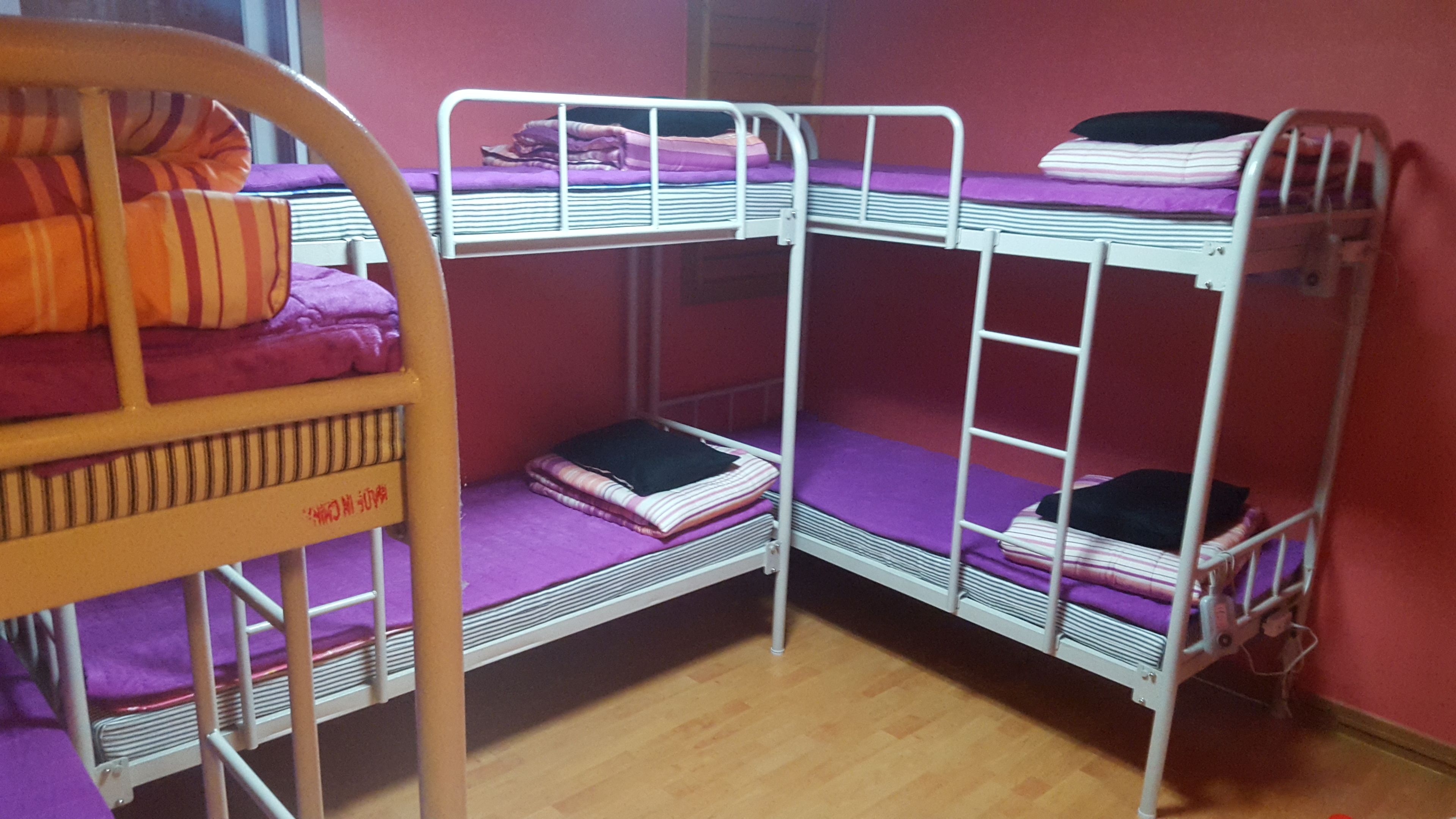 Quarto com beliche, duas camas, cada uma com colchão roxo e roupa de cama listrada.