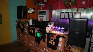 A brick counter with a neon sign, a JMC speaker, and various items on display. - gangneung sol guesthouse - Hostel (Gangneung)