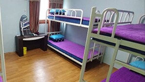 Een slaapkamer met stapelbed, houten vloer, een bureau en een stoel.