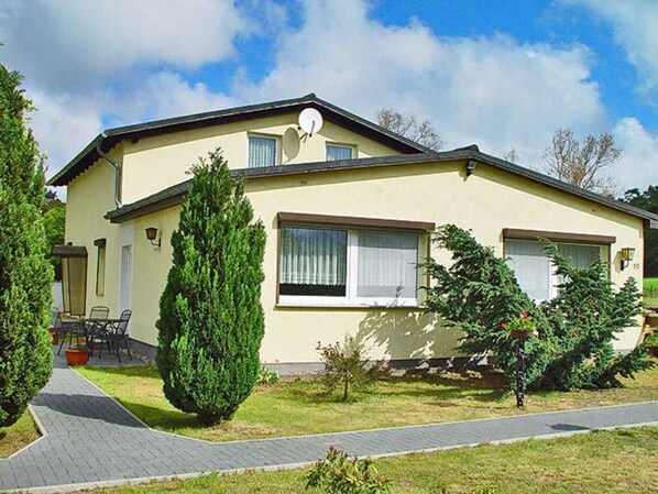 A two-story house with a paved driveway, a satellite dish, and a small patio area.