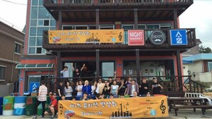 A group of people gathered in front of a building with a sign for a Night Market Beer Pub and a music event. - Donghae Sol Guesthouse - Hostel (Donghae)