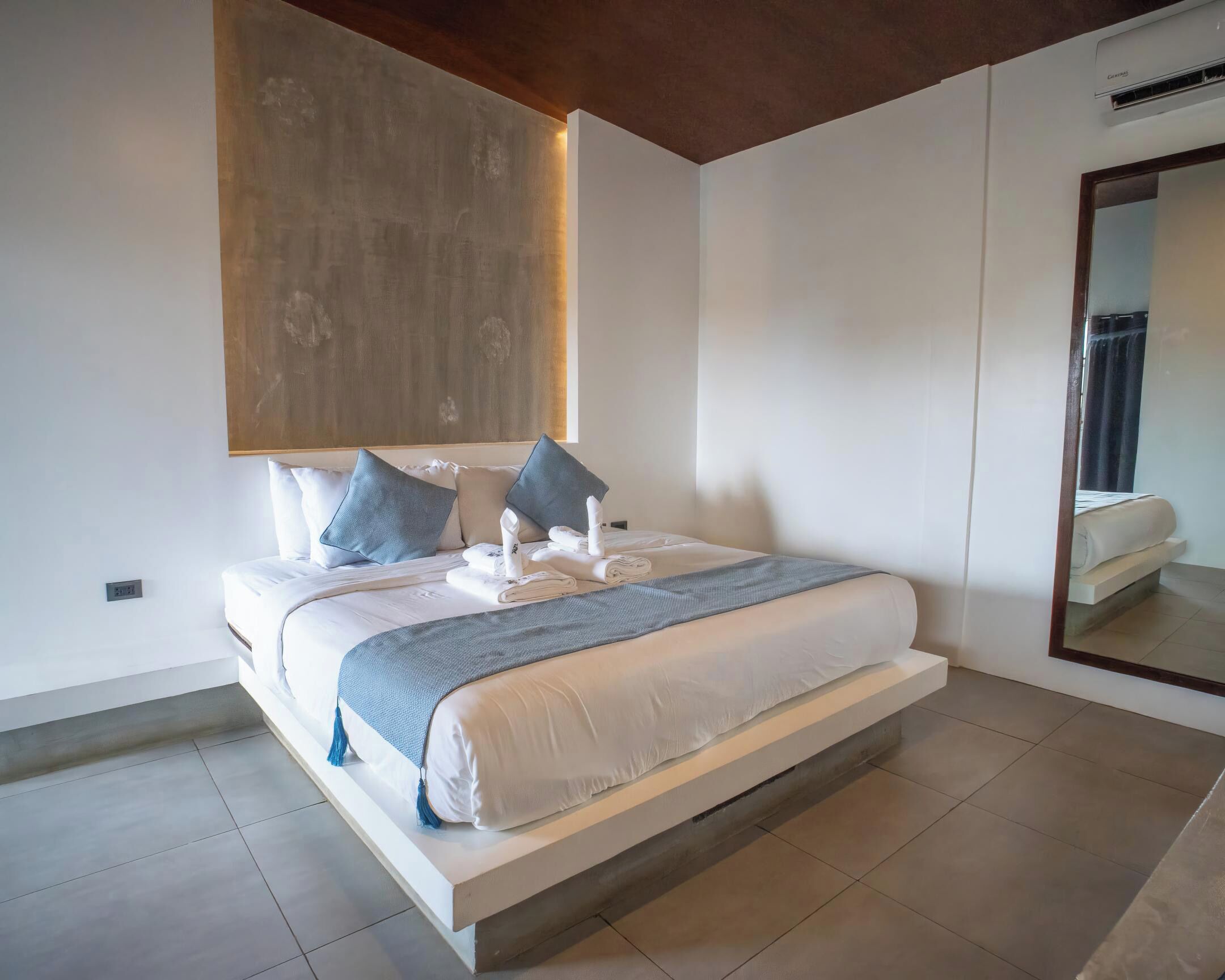 A modern bedroom with a large bed, a wooden ceiling, and a large mirror.