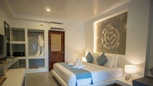 A modern hotel room with a bed, a desk, a wardrobe, and a wall-mounted artwork. - Amihan Resort (Panglao)