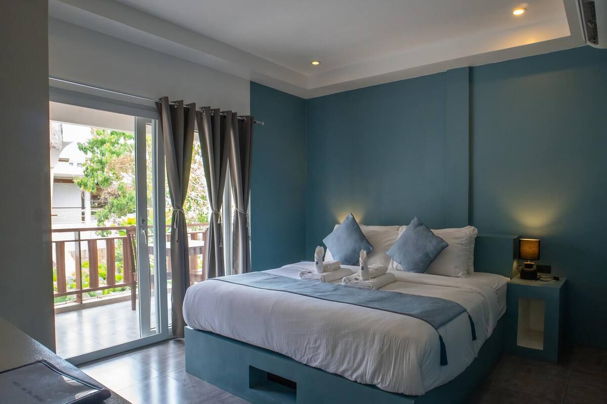 A modern bedroom with a bed, a nightstand, and a view of the outdoors.