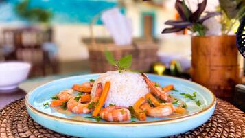 A plate of white rice topped with shrimp and carrots, garnished with herbs, on a blue plate.