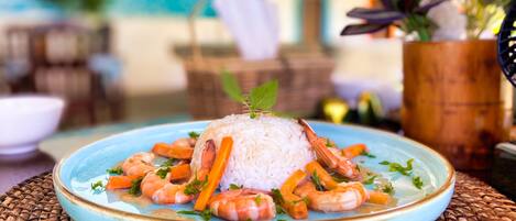 A plate of white rice topped with shrimp and carrots, garnished with herbs, on a blue plate.