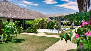 A resort with thatched-roof buildings, a pool, and a well-maintained garden. - Amihan Resort (Panglao)