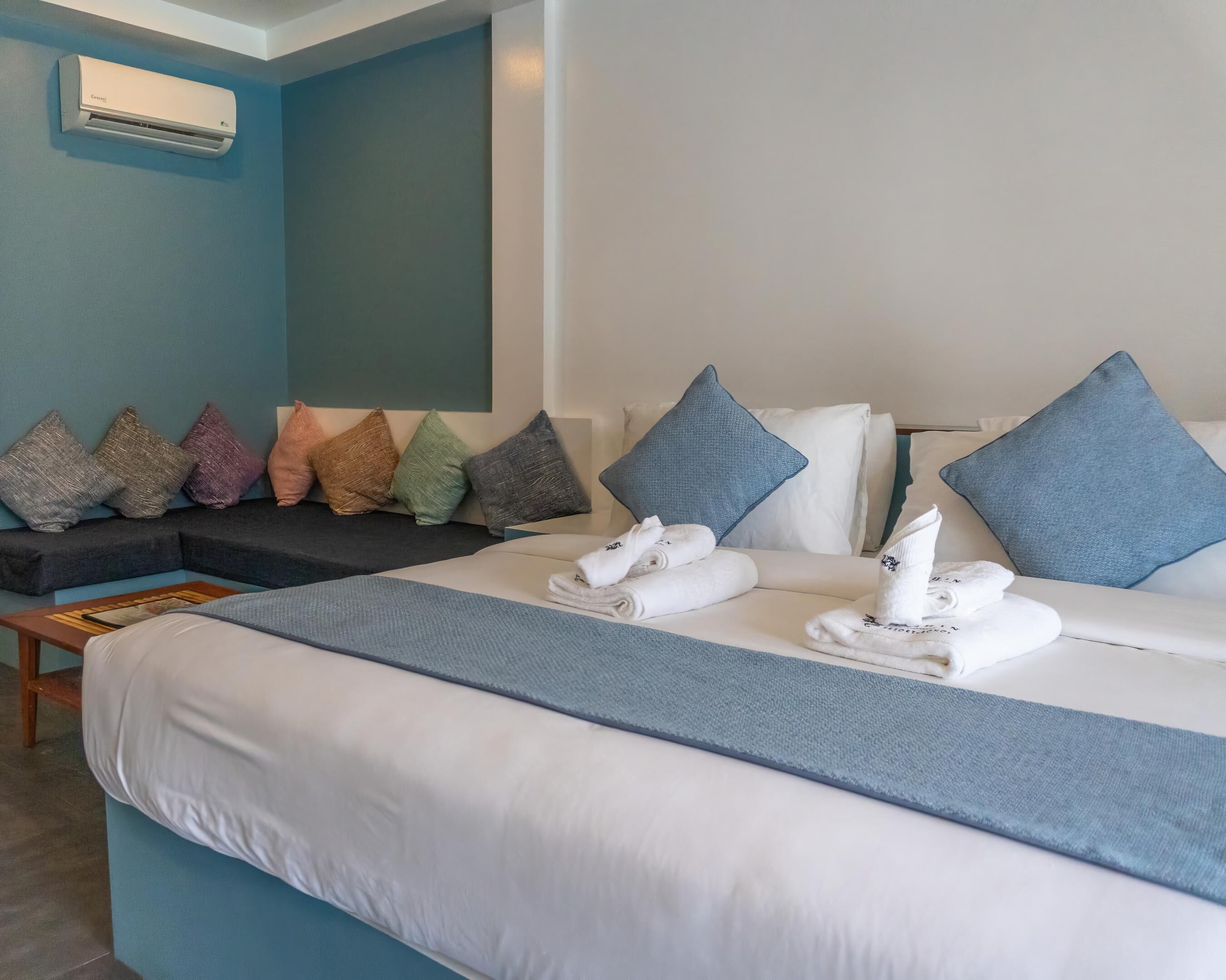 Una habitación de hotel con cama, almohadas, sofá y aire acondicionado.