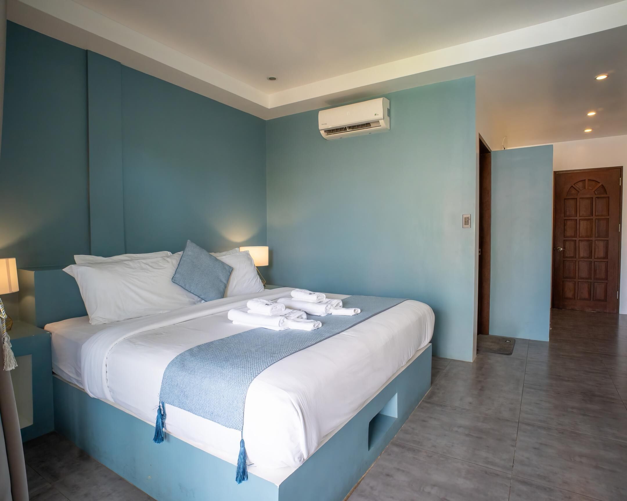 A bedroom with a bed, pillows, a bedside lamp, and a towel on the bed.