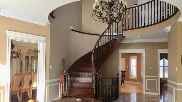 Un vestíbulo amplio con una imponente escalera, un candelabro y un comedor.