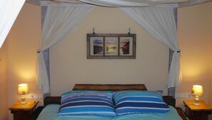 A bedroom with a bed, two bedside tables, a nightstand, a wall-mounted picture frame, and white drapes. - Family vacation in "Röbel's most beautiful house 2017"  (Röbel/Müritz)