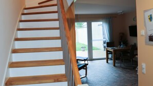 A staircase with wooden steps and a handrail, leading to a room with a dining table and chairs. - Family vacation in "Röbel's most beautiful house 2017"  (Röbel/Müritz)