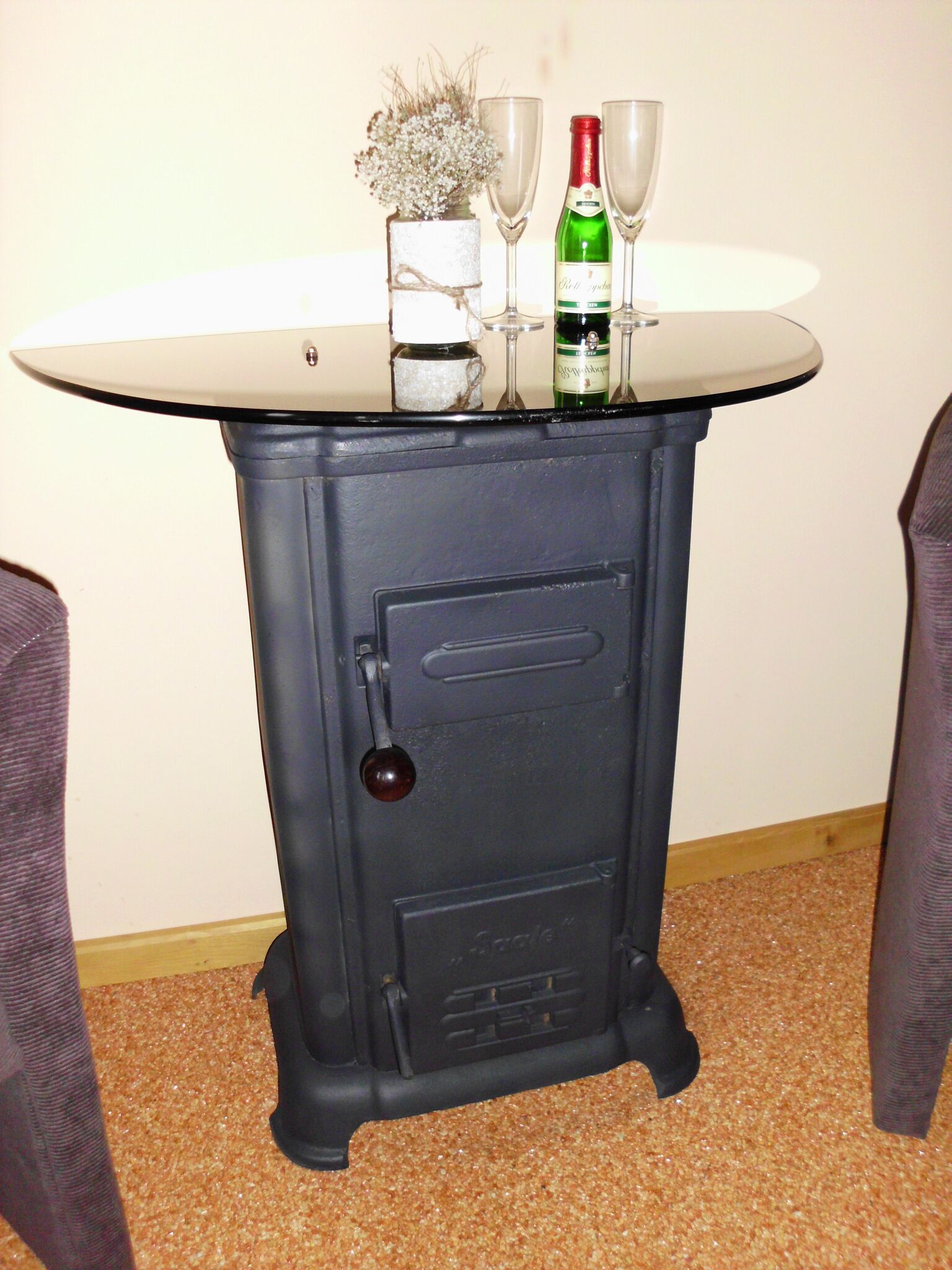 Une vieille cuisinière à gaz avec une table posée dessus, deux verres à vin et une bouteille de vin.