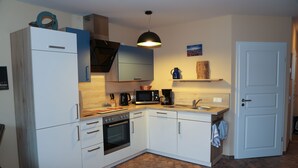 A compact kitchen with white cabinets, a built-in oven, a microwave, and a coffee maker. - Family vacation in "Röbel's most beautiful house 2017"  (Röbel/Müritz)