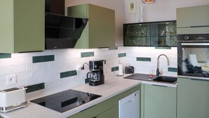 Eine Küche mit einem schwarzen Herd, einer Kaffeemaschine, einem Spülbecken und einem Toaster.