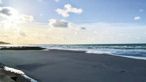 Ein Strand mit klarem Himmel, Wellen und einer fernen Küste.