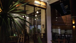 A coffee shop interior with a wooden sign reading "OUTLIGHT COFFEE," glass doors, and interior lighting. - De House Hotel (Sibu)