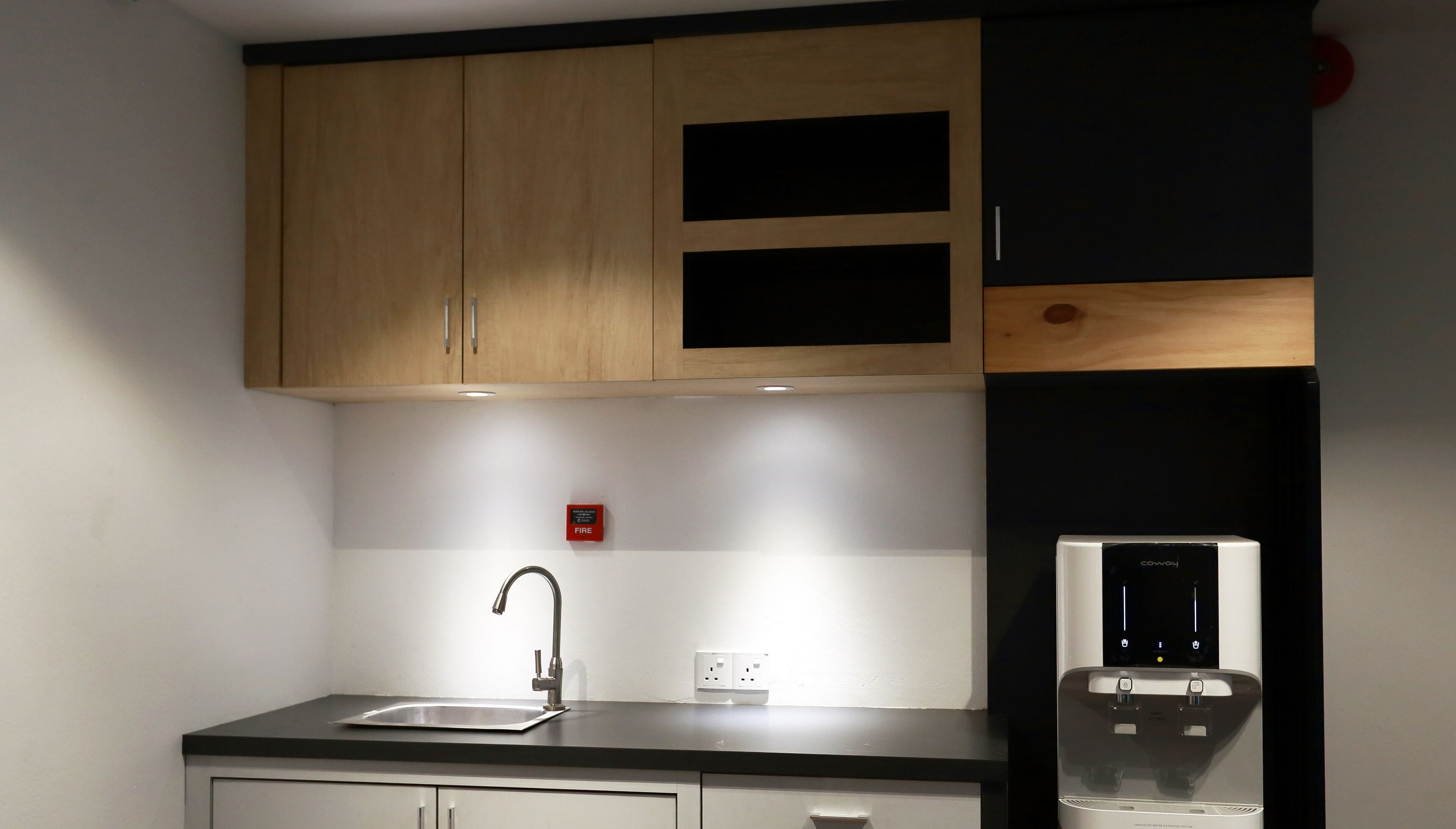 A kitchen with wooden cabinets, a stainless steel sink, and a water dispenser.