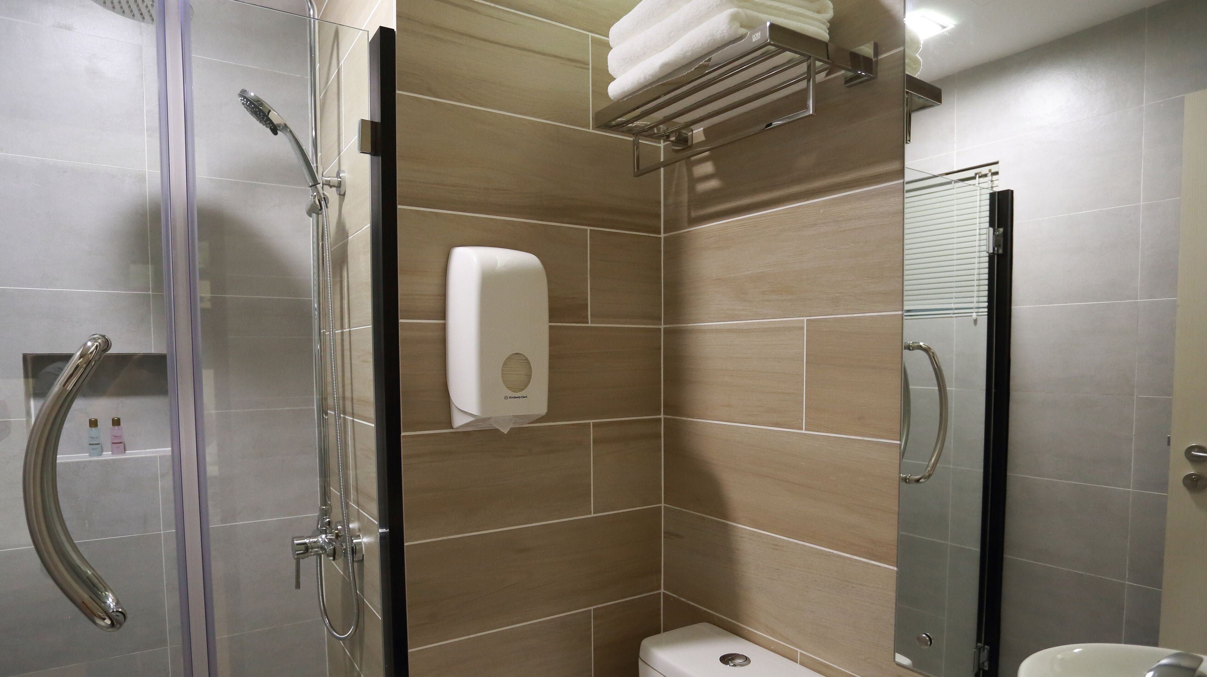 Un baño moderno con cabina de ducha de vidrio, un inodoro y un secador de manos.