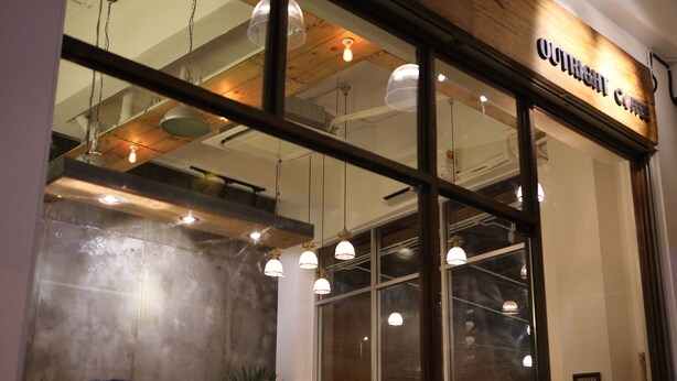 A coffee shop with a modern interior, large windows, and hanging pendant lights. - De House Hotel (Sibu)