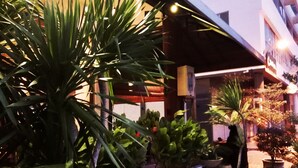A hotel entrance with a covered outdoor area, potted plants, and a sign above the entrance. - De House Hotel (Sibu)