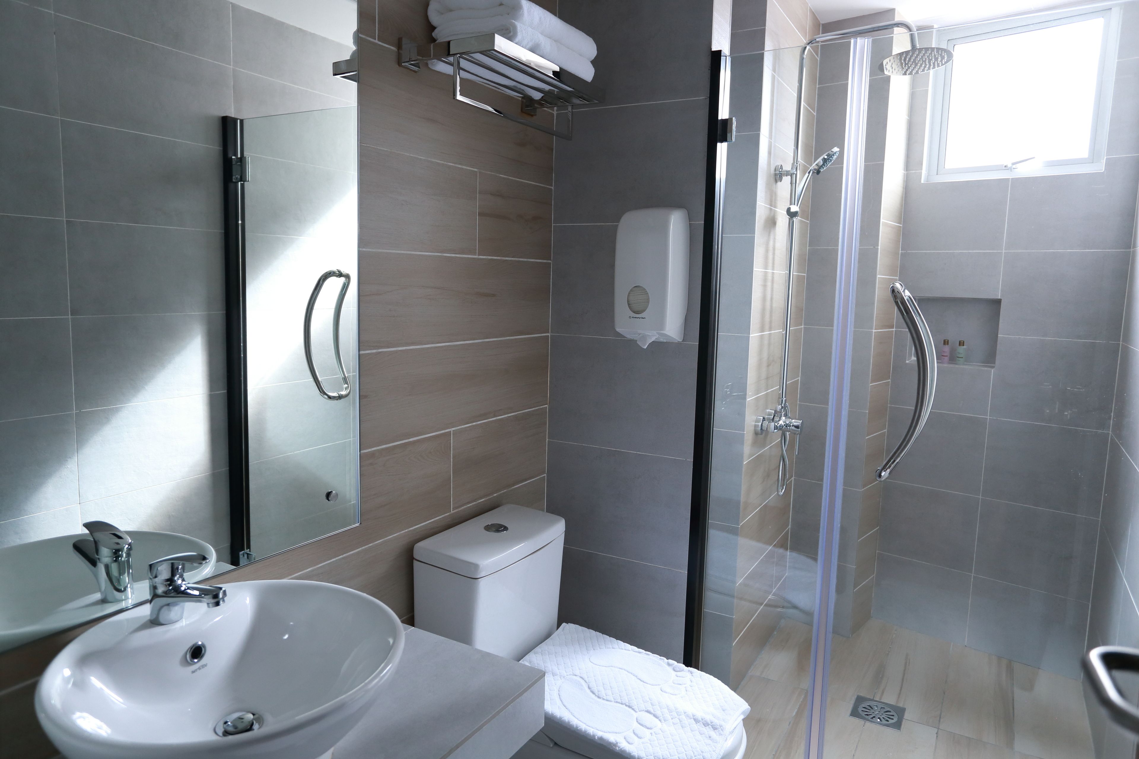 Ein modernes Badezimmer mit einer Duschkabine aus Glas, einem weißen Waschbecken und einer Toilette.