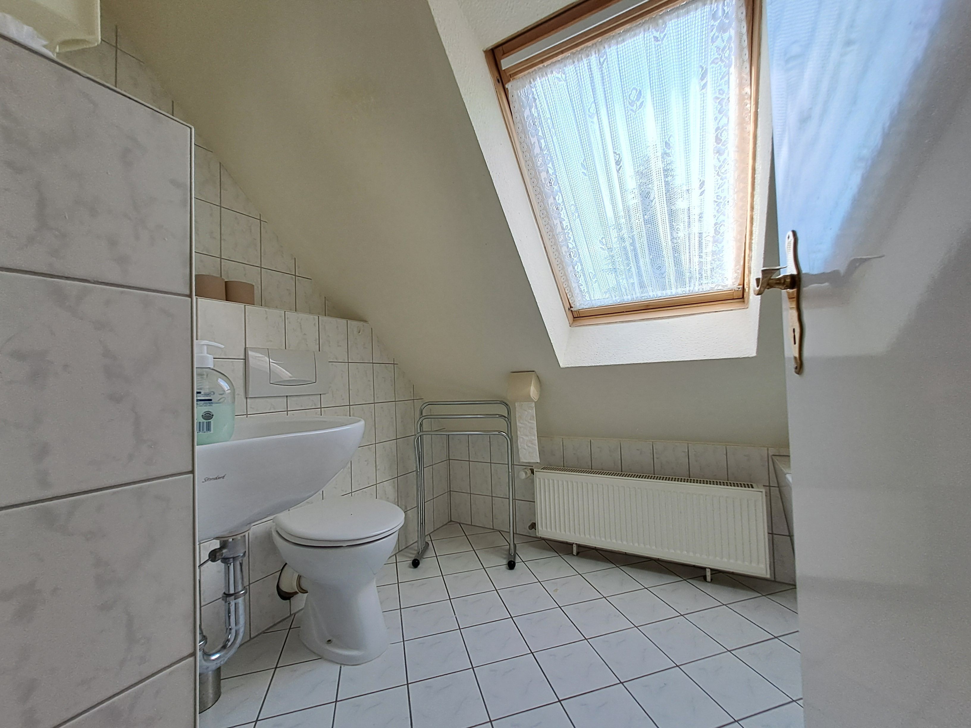 A small, modern bathroom with a toilet, sink, and window.