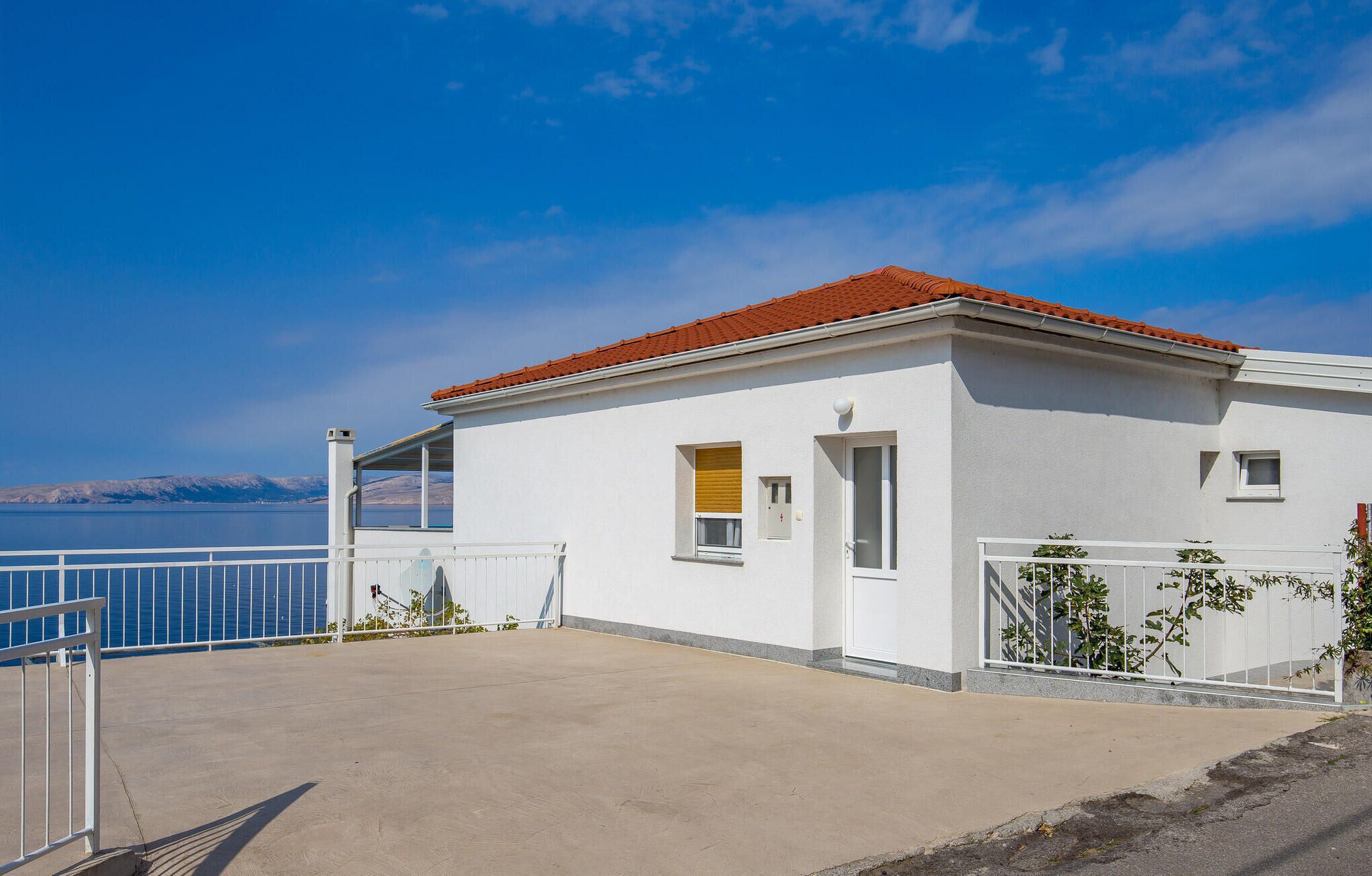 Un edificio blanco con techo rojo, un balcón y vista al mar.