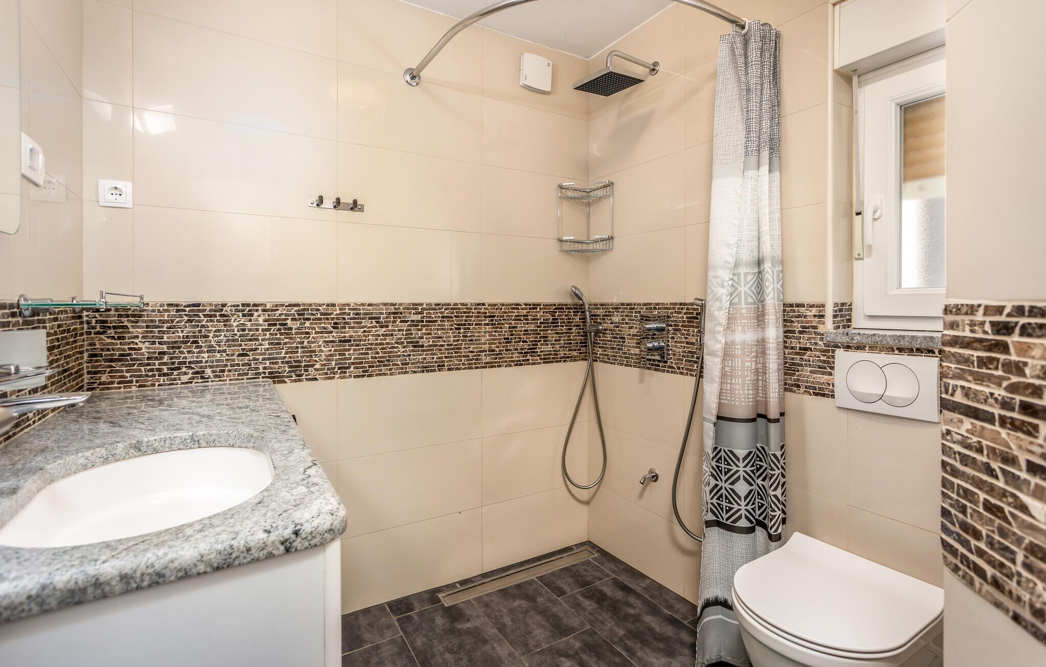 A bathroom with a shower, a toilet, and a sink.