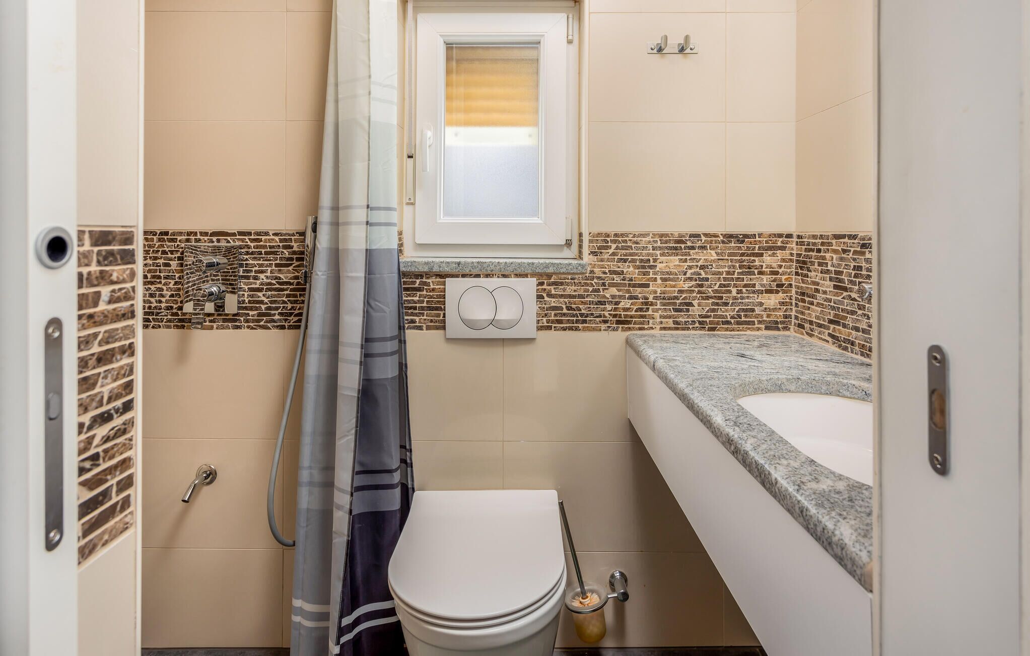 Une petite salle de bain comprenant des toilettes, un lavabo et un rideau de douche.
