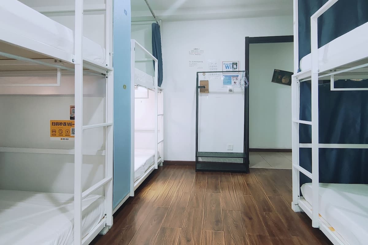 A room with bunk beds, a wooden floor, and a door with a Wi-Fi sign.