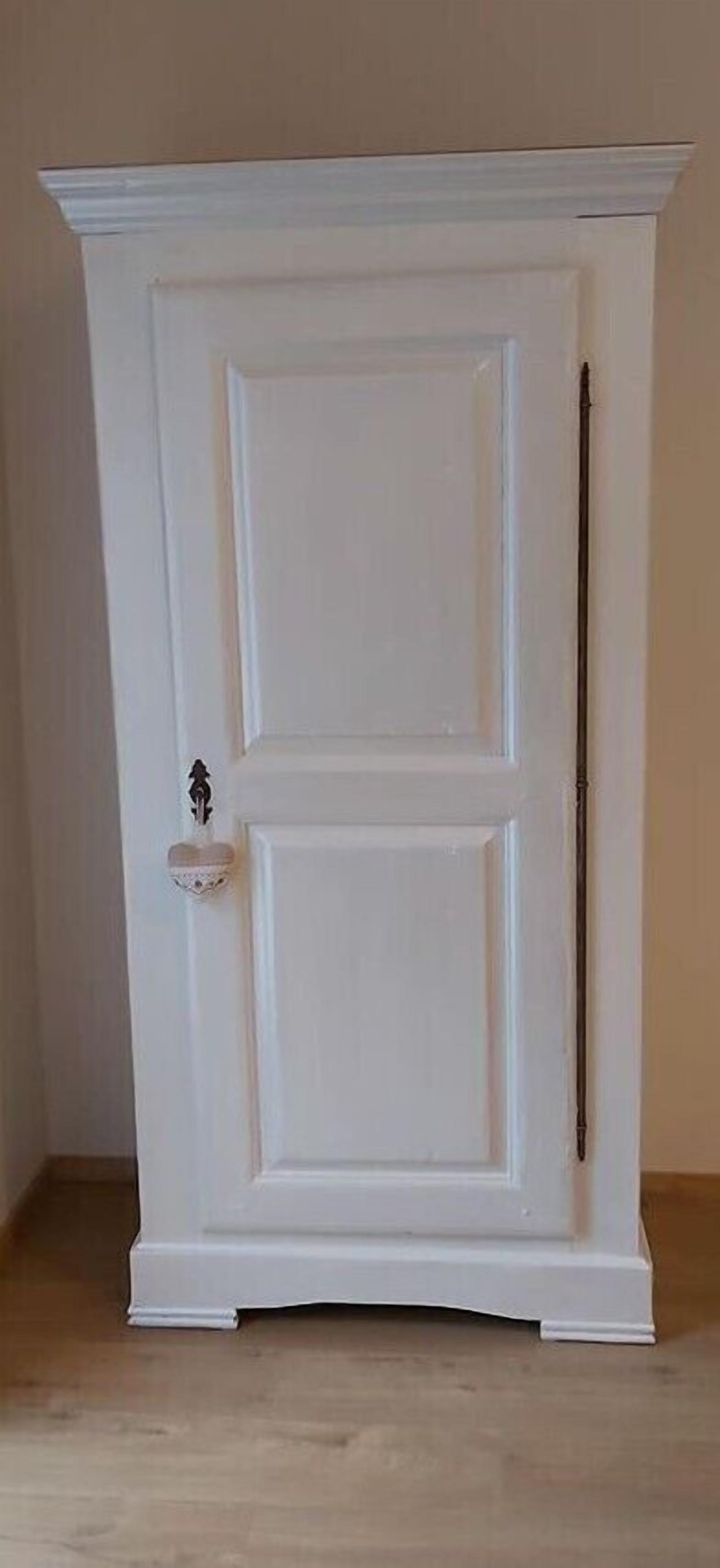 A white, double-door cabinet with a small decorative item on the left door.