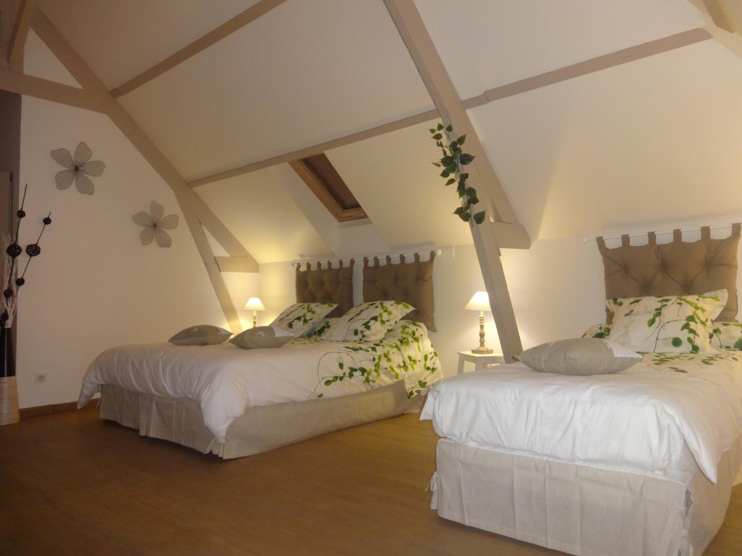 Une chambre avec deux lits, des poutres en bois au plafond et une plante accrochée au mur.