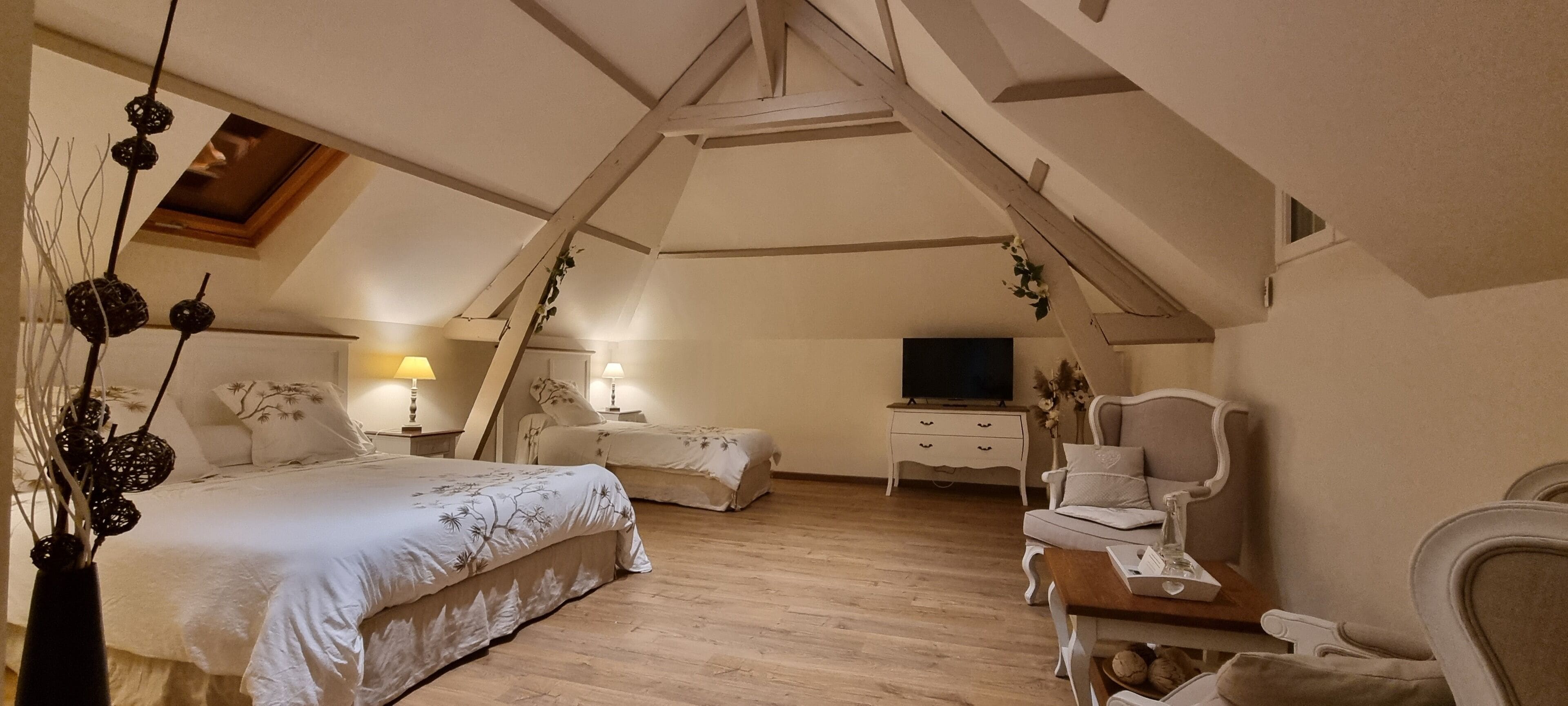 A bedroom with two beds, a TV, a chair, and a wooden ceiling.